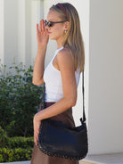 Side view of black leather studded crossbody bag