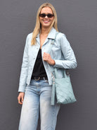 Cadelle Carter pale blue leather handbag worn over pale blue leather jacket